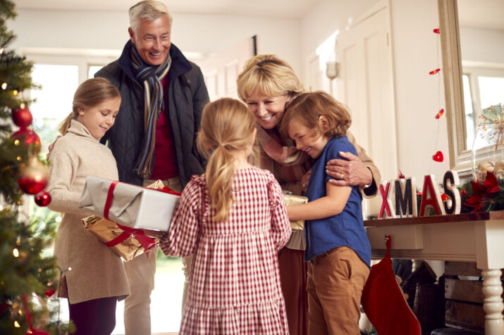 Grandchildren Greeting Grandparents As They Arrive With Presents To Celebrate Family Christmas