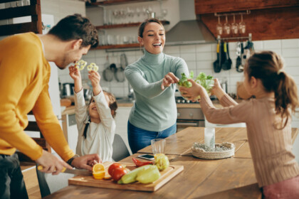 Home remodeling services that provide more family space. Happy parents and their daughters having fun while preparing meal together at home.